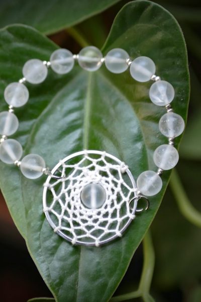 bracelet blanc attrape-rêve et perles sur feuille verte